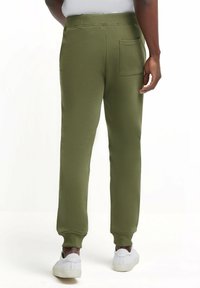 Olijfgroene joggers met een taps toelopende pijp, elastische tailleband en een enkele achterzak, gemaakt van een zachte katoenmix met ribbelmanchetten.