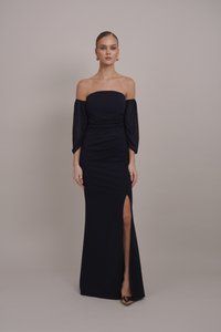 Robe bleu marine à épaules dénudées avec de longues manches amples, fente haute sur la cuisse et silhouette ajustée, fabriquée en tissu lisse et extensible.