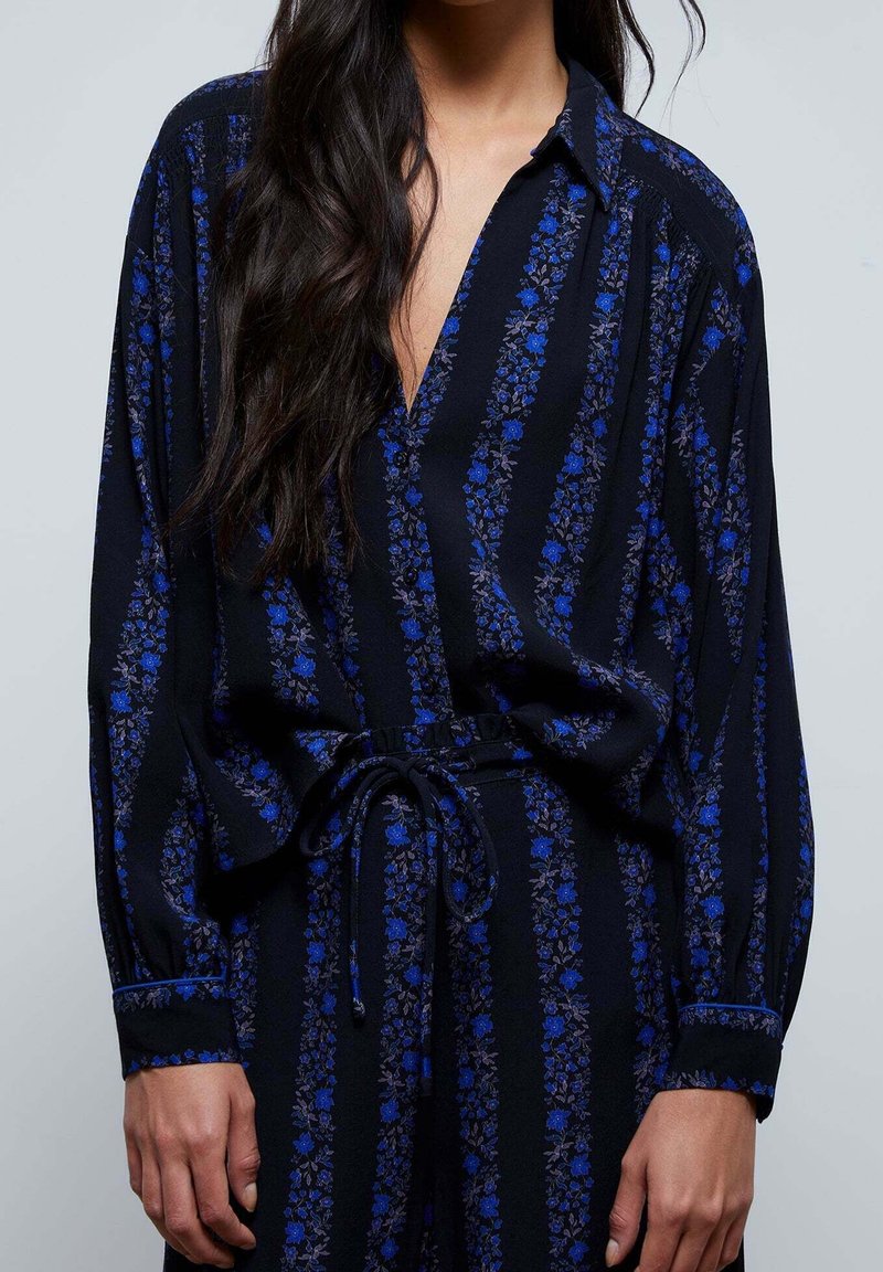 Schwarze Button-Down-Bluse mit blauem Blumenmuster und vertikalen Streifen, mit langen Ärmeln, einem Bindegürtel in der Taille und einem lockeren Schnitt.