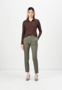 Brown ribbed long-sleeve polo shirt paired with tailored olive green pants and taupe pointed-toe heels, creating a streamlined silhouette.