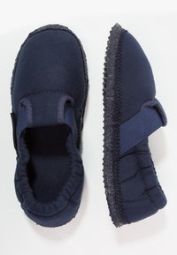 Marinelblauwe instappers met een zachte stoffen bovenkant, elastische opening en een getextureerde rubberen zool. Voorzien van een gevoerde binnenkant voor comfort.