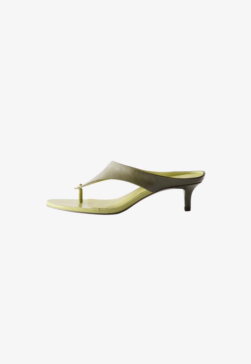 Sandale string vert clair élégante avec un petit talon kitten et une large bride traversant le pied, vue de profil sur fond blanc.
