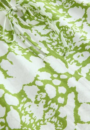 Witte stof met een groen onregelmatig gespikkeld patroon, met een centrale trekkoordsluiting en een zachte textuur.