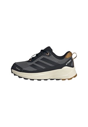 Svart og grå atletisk sko med teksturert stoff, tre svarte striper, en dempet såle og en beige hælakkent. Inkluderer snøring.