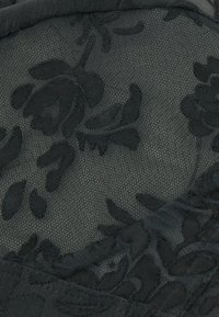 Černá květinová krajka s texturovaným vzorem a vyvýšenými květinovými motivy. Základ má jemnou, síťovou vazbu.