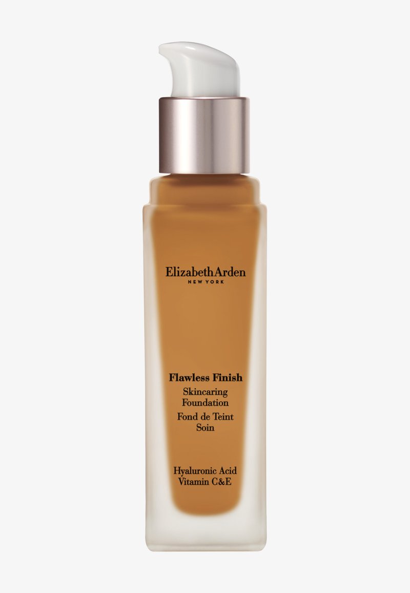 Fond de teint soin "Flawless Finish" dans une bouteille en verre transparent avec une section en ambre mat. Présente une pompe blanche et une étiquette avec du texte noir.