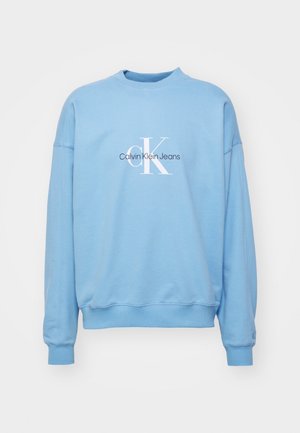 Jasnoniebieska bluza z długim rękawem z prążkowanymi mankietami, okrągłym dekoltem i logo "Calvin Klein Jeans" nadrukowanym na piersi w białym i czarnym kolorze.