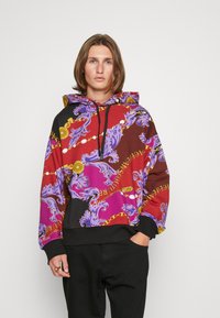 Hoodie met een mix van rode, paarse en zwarte kleuren. Patronen bevatten sierlijke ontwerpen en gouden kettingen. Zwarte manchetten en tailleband.