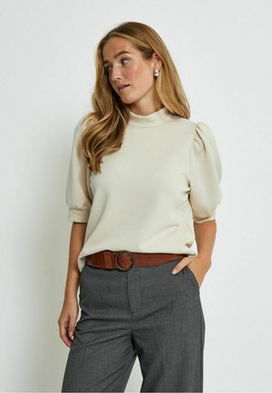 Cream puff-sleeve top with a high neckline paired with gray trousers and a brown belt featuring a round hardware detail. Smooth fabric texture.