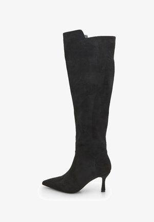 Botte haute en suède noir avec un bout pointu, un talon stiletto élancé et un haut structuré. Texture lisse, design minimaliste sans embellissements.