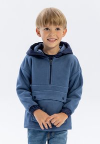 Pullover in pile blu con zip a metà, cappuccio blu navy, polsini elastici e tasca frontale con due bottoni a pressione. Texture liscia.