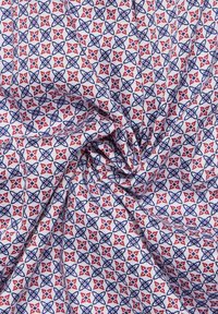 Baumwollstoff mit weißem Hintergrund, der ein sich wiederholendes Muster aus blauen und roten Blumenmotiven zeigt und ein texturiertes Aussehen verleiht.