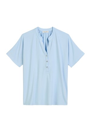 Chemise bleu clair à manches courtes en tissu doux, avec un col henley et quatre boutons sur le devant, offrant une coupe décontractée.