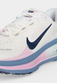 Λευκό παπούτσι Nike για τρέξιμο με ναυτικό λογότυπο, ροζ λεπτομέρειες, ανοιχτό μπλε σόλα και κορδόνια. Ορατά τα «Run» και «vomero 10» στη γλώσσα.