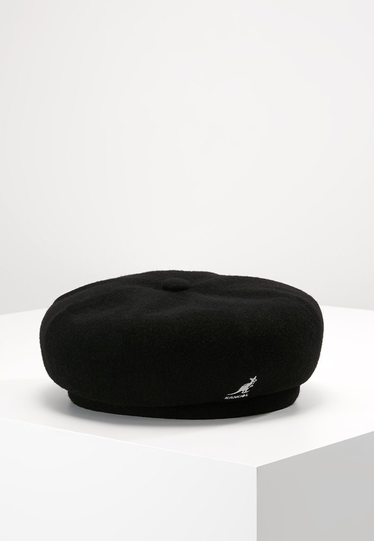 Beret de lana negra con forma redonda y plana. Presenta un botón central y un logo de canguro bordado. Textura suave con un acabado liso.