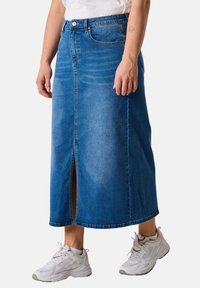 Denim midi skirt in dark blue, featuring a front slit and stitching details. Worn with light gray sneakers for a casual look.