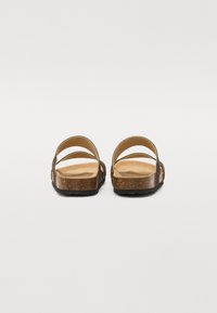 Brune korksandaler med to brede stropper, en teksturert fotseng og en svart gummisåle. Designet er åpen bak og minimalistisk.