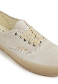 Beige mokka-tennarit kumipohjalla, pyöreällä kärjellä, beigeillä nauhoilla ja hopeanvärisillä rei'illä. Sivussa on pieni Vans-logo.