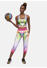 Kolorowy strój sportowy z żywym topem bez rękawów i legginsami 3/4 z różowym pasem. Wzór zawiera plamy zieleni, niebieskiego i różowego.