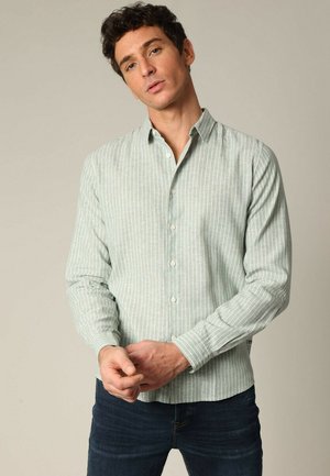 Chemise à manches longues rayée vert clair avec un col boutonné, fabriquée dans un tissu à texture lisse. Présente un design ajusté.