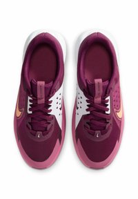 Scarpe da ginnastica maroon e rosa con tomaia in rete, dettagli bianchi, design testurizzato e lacci viola, dotate di un logo a forma di swoosh dorato.