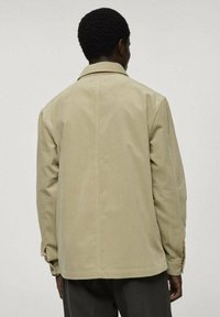 Beige corduroy jas met een kraag, lange mouwen en een relaxte pasvorm. Kenmerkt zich door verticale ribbelstructuur en een rechte zoom.