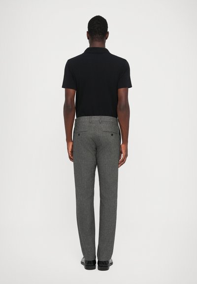Schwarzes Poloshirt mit kurzen Ärmeln, kombiniert mit grauen, strukturierten Anzughosen. Die Hosen haben einen geraden Schnitt und Gesäßtaschen.