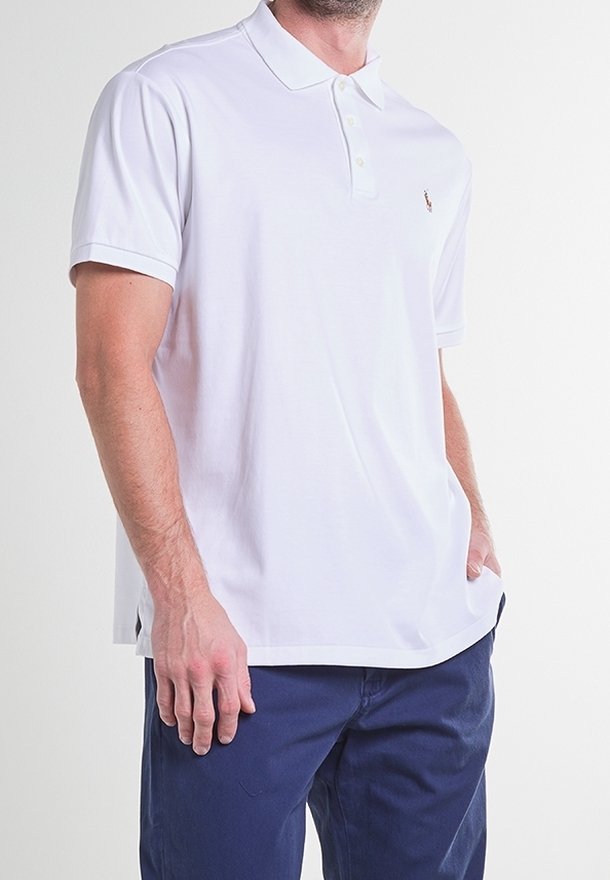Polo blanc en tissu de coton, manches courtes, patte de boutonnage à deux boutons, et petit logo sur le côté gauche de la poitrine. Coupe ajustée avec fentes latérales.