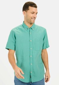 Korte mouwen, overhemd met kraag in teal. Gemaakt van lichtgewicht stof met een knoopsluiting aan de voorkant en een enkele borstzak. Zachte, gestructureerde afwerking.