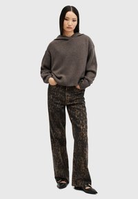 Hoodie marrone oversize con bordo a costine, abbinato a pantaloni a gamba larga con stampa leopardata nera e ballerine nere a punta.