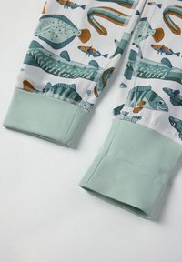 Kinderhosen mit einem Fischmuster in Grün, Blau und Orange. Die Bündchen bestehen aus einem weichen mintgrünen Material mit glatter Textur.