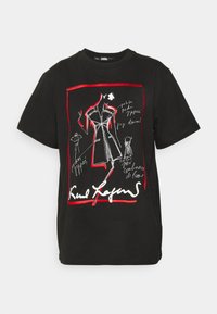 Camiseta de algodón negra con un diseño gráfico en blanco y rojo que incluye bocetos de moda y texto, de mangas cortas y con cuello redondo.