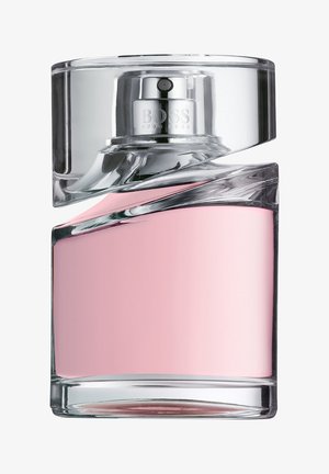 Heldere glazen parfumfles met een gebogen ontwerp, met een roze binnensectie en een zilveren spuitmondje. Aangevuld met een doorzichtig dop.