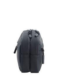 Bolsa negra de doble cremallera con una textura suave y mate y una forma rectangular compacta. Presenta un branding sutil en el lateral.