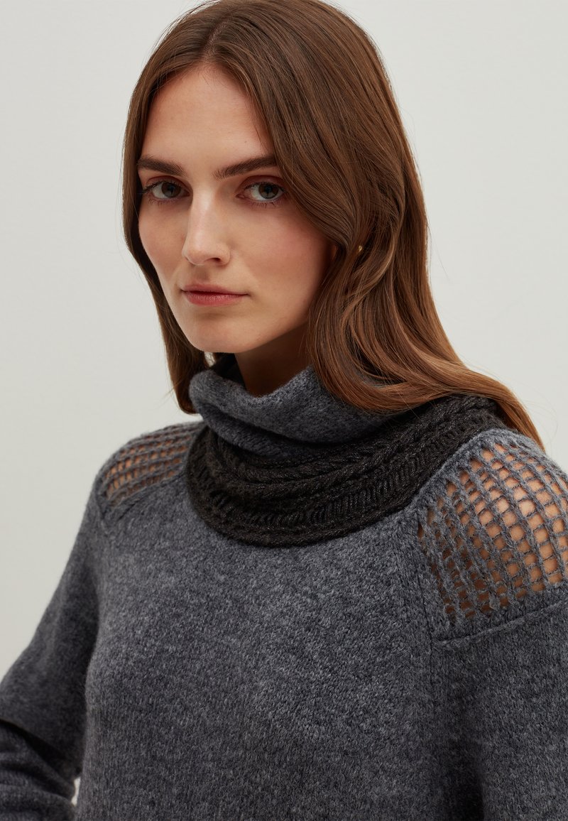 Maglione grigio scuro con collo alto e a ruota, con dettagli in maglia testurizzata sulle spalle e un motivo a maglia aperta. Materiale morbido e caldo.