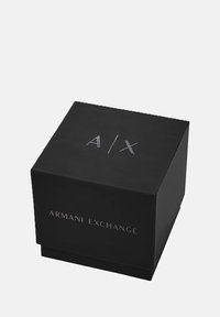 Sort firkantet æske med sølv Armani Exchange-logo og A|X-initialer på toppen mod en hvid baggrund.