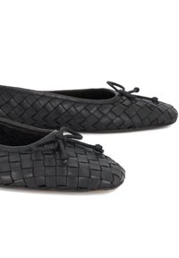 Black woven leather ballet flats featuring a round toe, small bow accent, and textured surface. Soft interior lining for comfort.