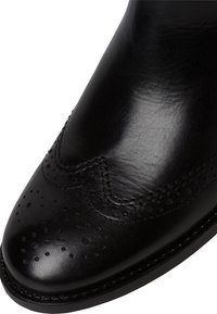 Chaussure habillée en cuir noir avec perforations brogue et couture détaillée sur le bout et le long des bords.
