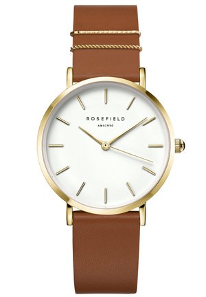 Montre ronde dorée avec un cadran blanc, bracelet en cuir brun, marqueurs d'heure minimalistes et une petite couronne sur le côté.
