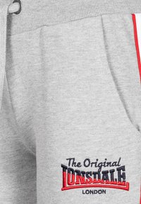 Pantaloni de trening gri cu buzunar frontal, talie cu șnur, dunga roșie pe lateral și logo brodat "The Original Lonsdale London".