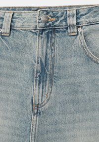 Világoskék farmernadrág elöl ezüst gombbal, övhurkokkal és narancssárga kontrasztos varrással a zsebek és a slicc körül.