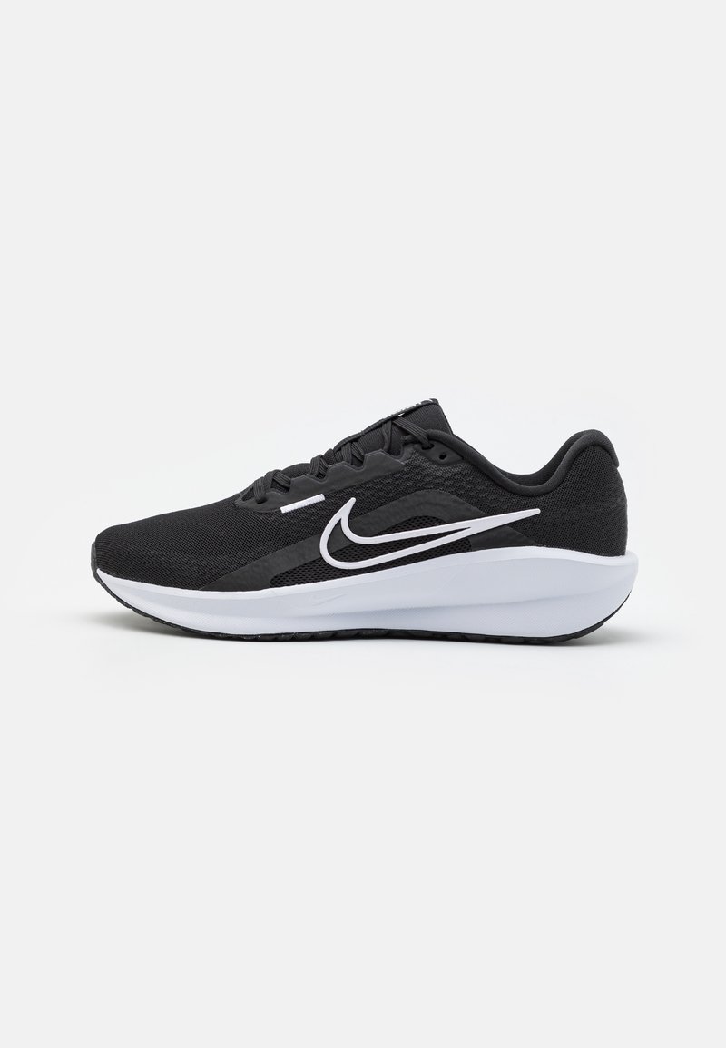 Chaussure de course basse noire avec semelle blanche et logo Nike swoosh blanc sur le côté, présentée sur un fond clair uni.