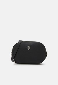 Borsa a tracolla nera con texture, zip argentata e logo "TH" sul davanti, dotata di una tracolla regolabile su uno sfondo bianco.