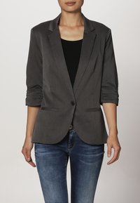Grijze, lichte blazer met een enkele knoopsluiting, geknipte revers en opgerolde mouwen. Bevat twee voorkruiken en een gladde textuur.