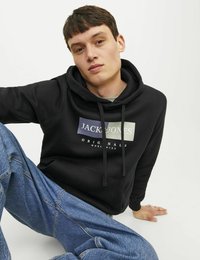 Czarna bluza z kapturem z troczkami, z prostokątnym nadrukiem logo w kontrastowych kolorach. Model w jasnoniebieskich dżinsach.