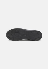 Black athletic shoe sole with textured patterns, including grooves and treads for traction. Made of rubber with a smooth finish.