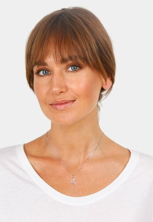 Silver necklace with a turtle pendant, featuring a delicate chain and a smooth texture, worn with a white v-neck shirt.