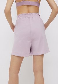 Fioletowe bawełniane szorty z elastycznym pasem i luźnym krojem. Charakteryzują się gładką teksturą i czystym wykończeniem, odpowiednie na co dzień.