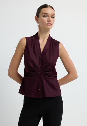 Sleeveless burgundy blouse with a wrap design and front buttons. Features subtle pleating on the sides, made from smooth fabric.