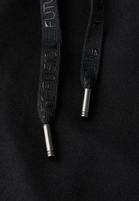 Black drawstrings with textured fabric and metallic tips resting on a black background, showcasing detail in the material and hardware.